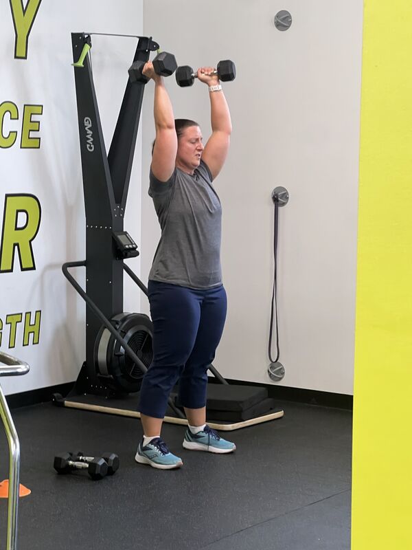 A member holding a medicine ball on the gym floor